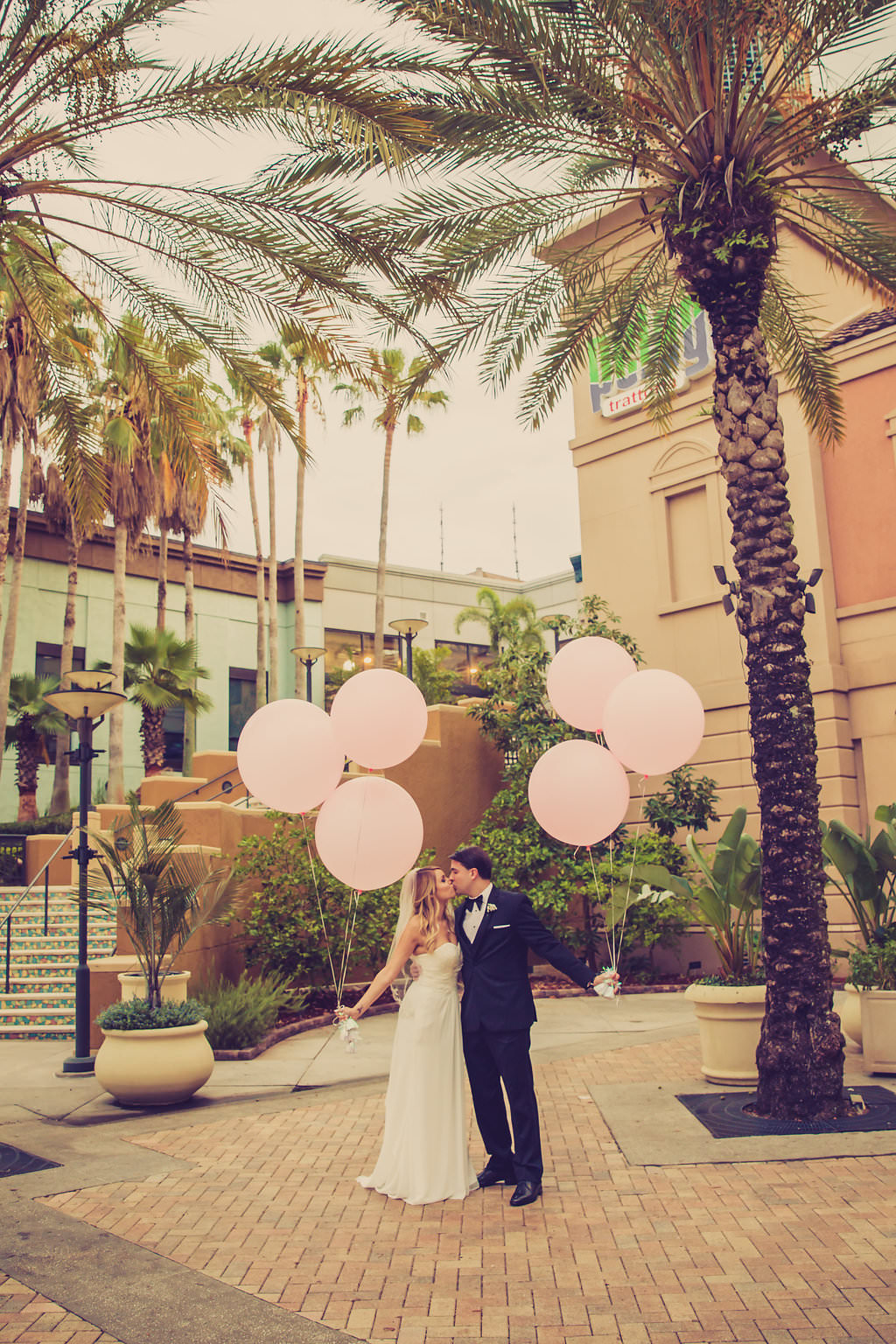 Outdoor Hotel Courtyard Wedding Portrait with Oversized Pink Balloons, Bride in Strapless Column Dress with White Bouquet | Venue The Tampa Renaissance