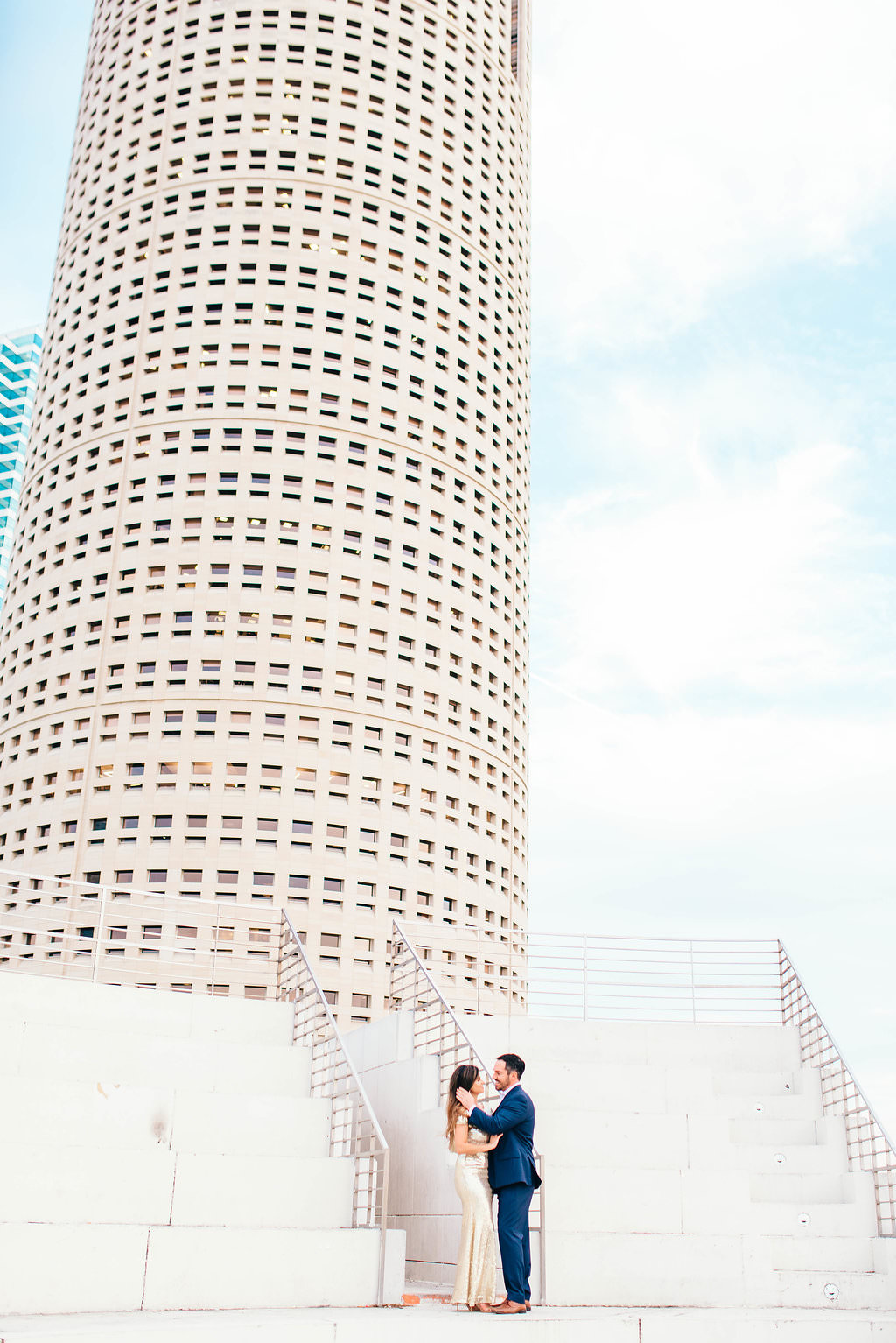 Downtown Tampa Riverwalk Classy Engagement Portrait, Bride in Long Gold Sequin Dress, Groom in Navy Blue Suit with Brown Leather Shoes