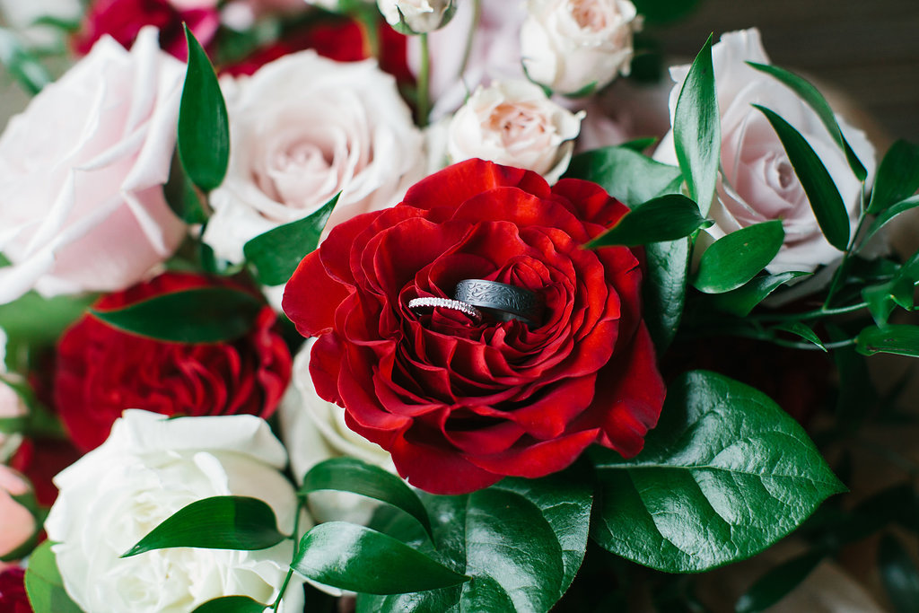 Carved Oxidized Silver Black Mens Wedding Ring and Diamond Wedding Band on Red and Pink Rose with Greenery Bouquet