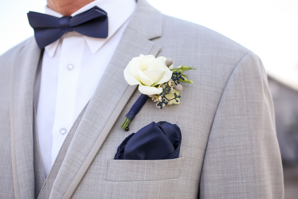 Outdoor Groom Portrait with White Rose with Blue Berry and Greenery Boutonniere, Navy Bow Tie and Pocket Square, and Light Gray Linen Suit | Tampa Bay Wedding Photographer Lifelong Photography Studios