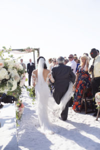 Siesta Beach Wedding Ceremony Portrait with Wood Folding Chairs, Peach, BLush, and White Rose with Natural Greenery Florals, and Ceremony Arch, Bride in Lace Applique Long Sleeve Dress | Sarasota Wedding Photographer Djamel Photography