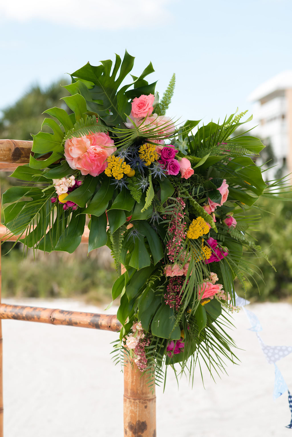 Outdoor Tropical Beach Wedding Bamboo Ceremony Arch with Pink and Yellow Florals with Greenery