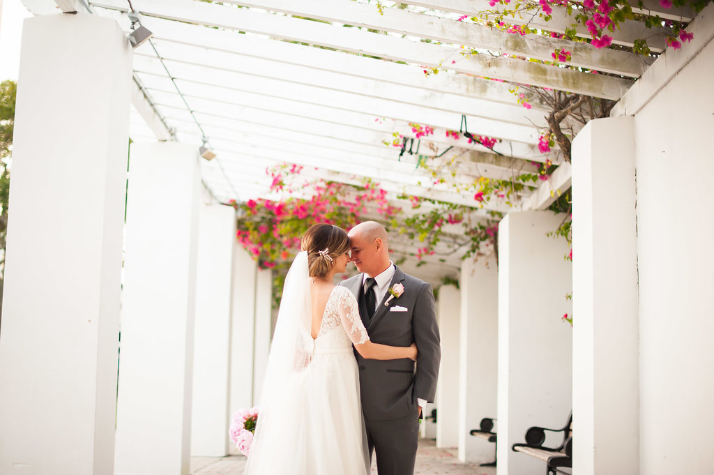 Outdoor Wedding Portrait, Groom in Gray Suit with Blush Pink Rose and Greenery Boutonniere, Bride in V Neck Lace Sleeve David's Bridal Dress | Downtown St Pete Wedding Ceremony Venue North Straub Park