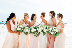 Outdoor Beach Bridal Party Portrait, Bridesmaids in Mismatched Blush Pink Dresses, Bride in Strapless Belted Dress, with White Floral and Natural Greenery Bouquet