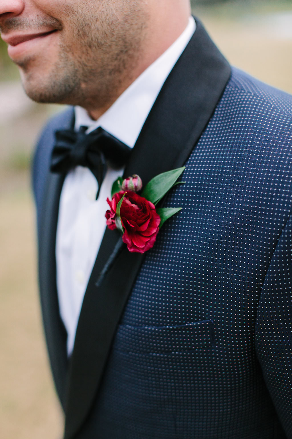 Outdoor Groom Portrait in Navy and White Dotted Suit, with Wine Red Rose with Greenery Boutonniere
