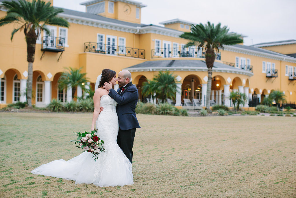 Outdoor Wedding Portrait, Groom in Navy and White Dotted Suit, with Wine Red Rose with Greenery Boutonniere, Bride in Strapless Mermaid Dress with Blush Pink and Red Rose with Greenery Bouquet | Venue Tampa Palms Golf and Country Club | Planner Parties A La Carte