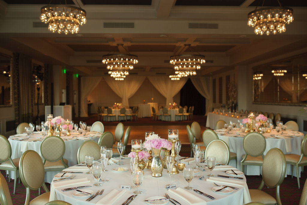 Hotel Ballroom Reception with Small Pink Peony Centerpieces in MIs-matched Gold Vases, with Thick Candleholders and Votive Candles and White Linens | Downtown St Pete Boutique Hotel Venue The Birchwood