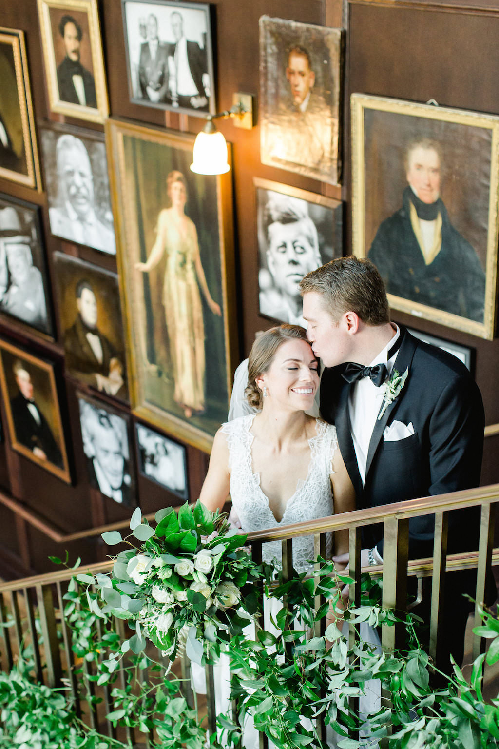 Indoor Wedding Portrait on Staircase with Greenery, Bride in V Neck Dress, Groom in Black Tuxedo | Tampa Wedding Photographer Ailyn La Torre Photography | Downtown Historic Venue The Oxford Exchange