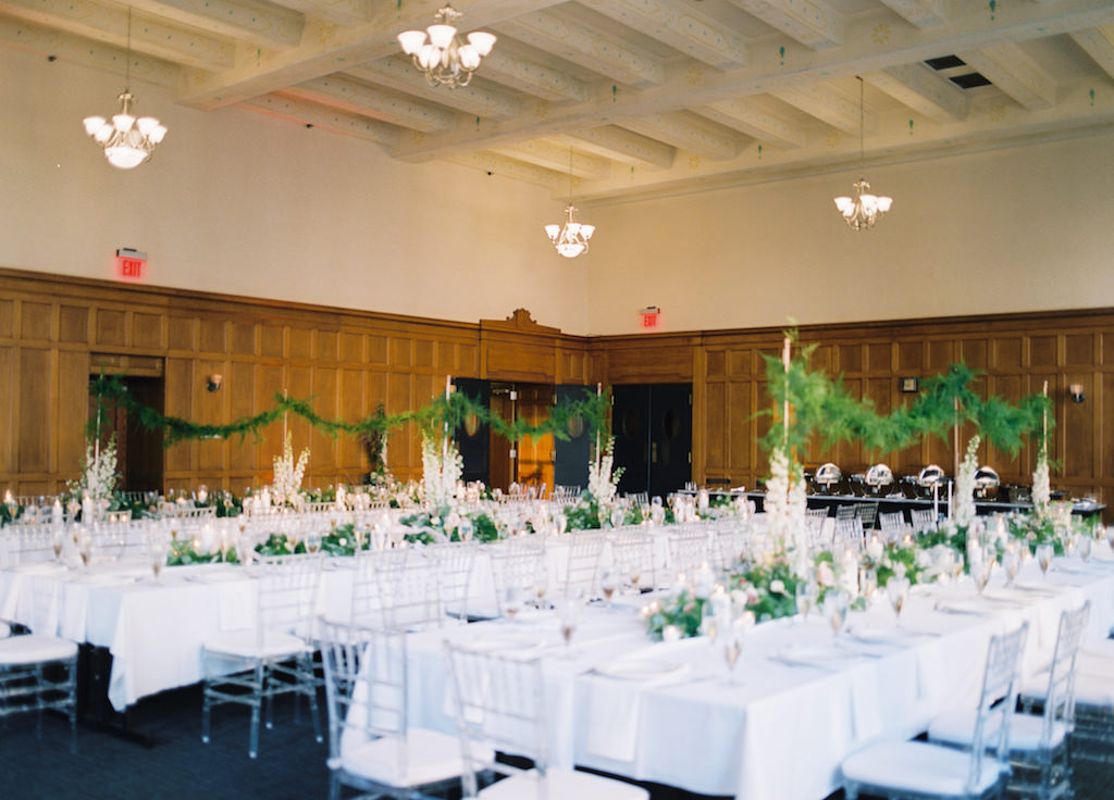 Hotel Ballroom White and Greenery Wedding Reception with Long Feasting Tables, Extra Tall White Spray and Garland Centerpieces, and Clear Chiavari Chairs | Historic Courthouse Downtown Tampa Hotel Venue Le Meridien