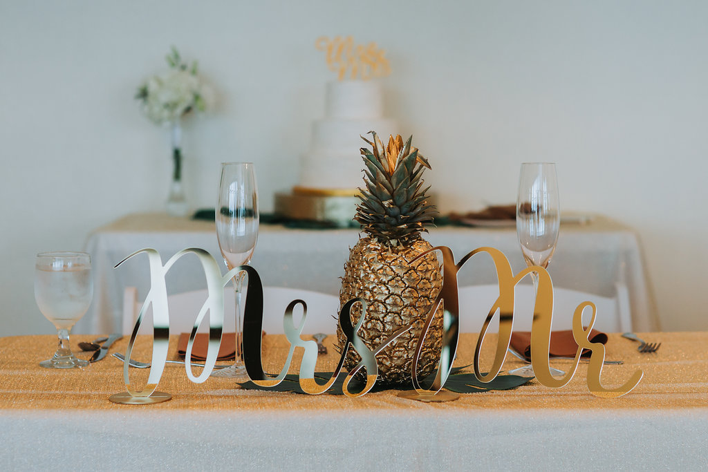 Tropical Wedding Reception Sweetheart Table with Oversized Mr and Mrs Gold Stylish Letters and Gold Painted Pineapple Centerpiece