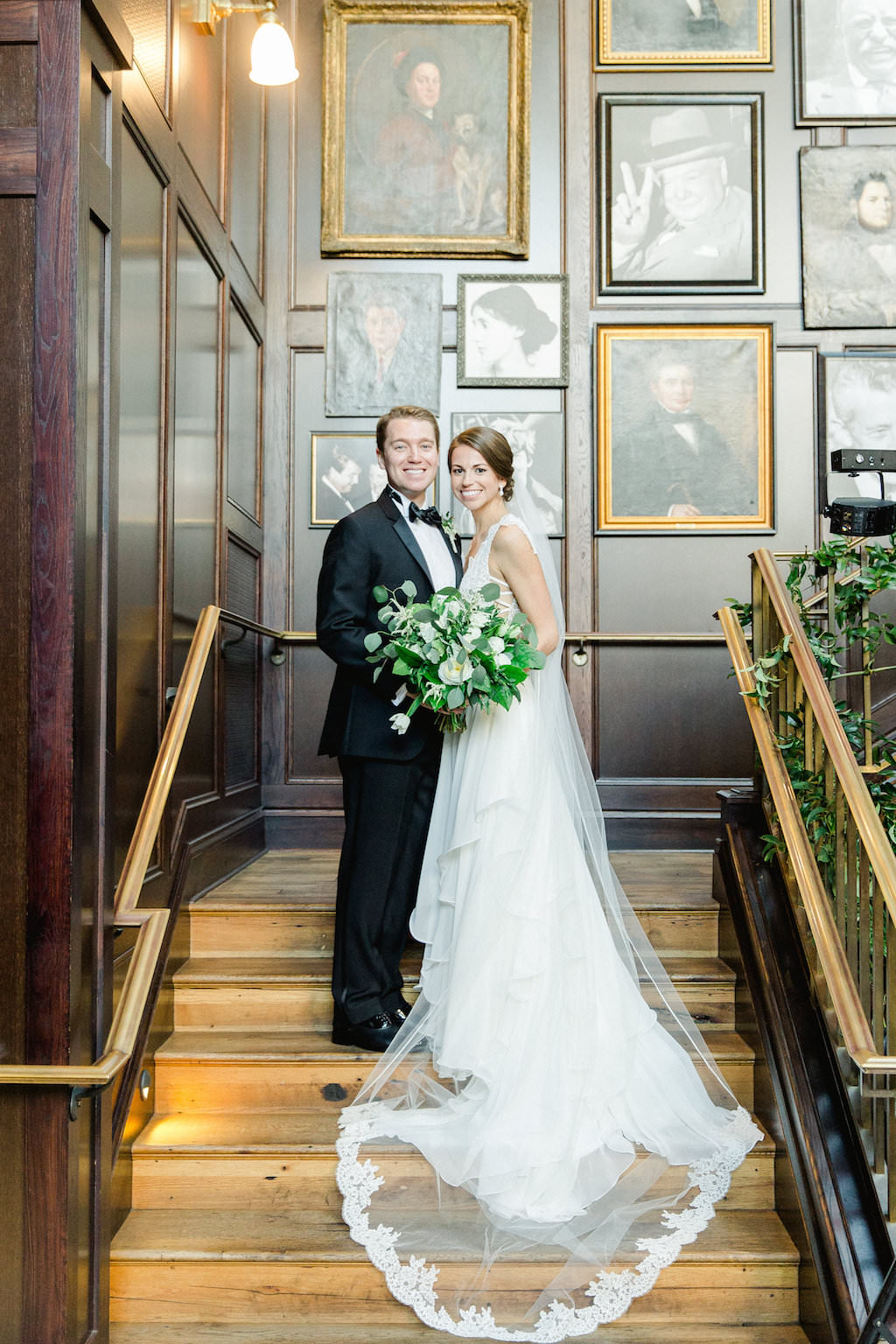 Indoor Wedding Portrait on Staircase with Greenery Bouquet , Bride in V Neck Lace Hayley Paige Dress, Groom in Black Tuxedo | Tampa Wedding Photographer Ailyn La Torre Photography | Downtown Historic Venue The Oxford Exchange