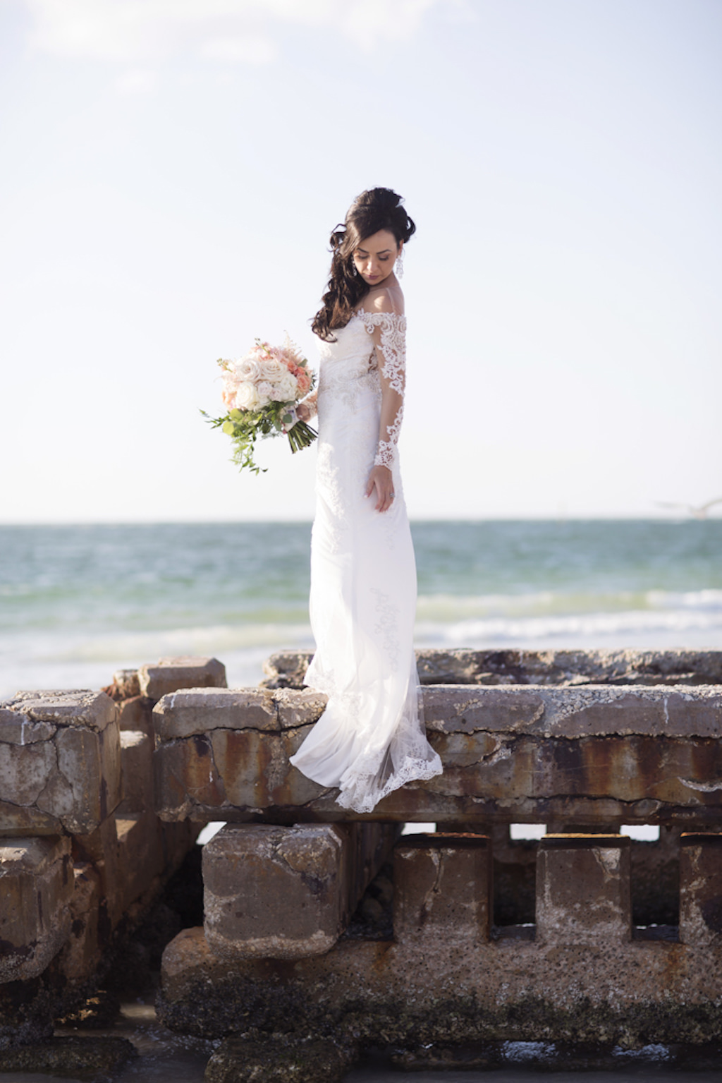Outdoor Beach Bridal Portrait, Bride in V Neck Off The Shoulder Lace Long Sleeve Brides by Demetrios Dress with Pink and White Floral Bouquet with Greenery | Tampa Bay Wedding Photographer Djamel Photography