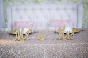 Beach Wedding Reception Sweetheart Table with Mr and Mrs Gold Glitter Letters, Sparkly Pink Linen, and Highbacked Loveseat Sofa