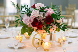 Red Wine, Pink and Ivory Rose Centerpiece with Greenery in Low Gold Vase, with Gold Table Number and Mercury Votive Candles | Tampa Bay Wedding Planner Parties A La Carte | Rentals A Chair Affair and Over The Top Rental Linens