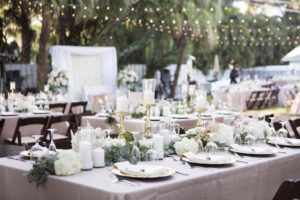 Outdoor Beach Wedding Reception with Blush Pink LInens, Gold Chargers and Candlesticks, Hurricane Lantern Candles and Greenery Garland Centerpiece with White Hydrangea Florals, and String LIghts | Siesta Key Wedding Venue Sunset Beach Resort