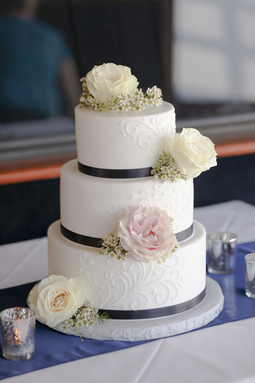 Three Tiered Round White Wedding Cake with Blush Pink and White Roses and Babys Breath Florals and Navy Blue Ribbon | Tampa Bay Unique Waterfront Nautical Wedding Venue Yacht Starship