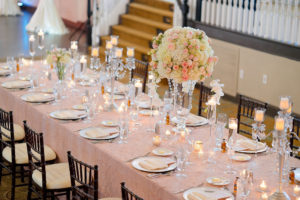 Hotel Ballroom Pink and Champagne Wedding Reception Long Feasting Table with Tall and Low Ivory and Pink Rose Centerpieces in Glass Vases with Greenery, Floating Votive Candles in Glass Holders and Candelabras, Black Chiavari Chairs | Textured Linen Rentals from Kate Ryan Linens | Historic Waterfront Hotel Wedding Venue The Don CeSar