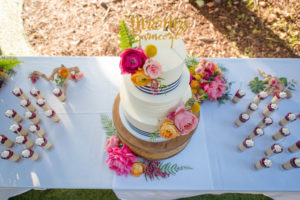 Three Tier Round White With Navy Blue Stripe Wedding Cake on Wooden Nautical Cake Stand with Stylish Custom Gold Caketopper with Pink and ORange Tropical Flowers with Ferns and Cake Shooters