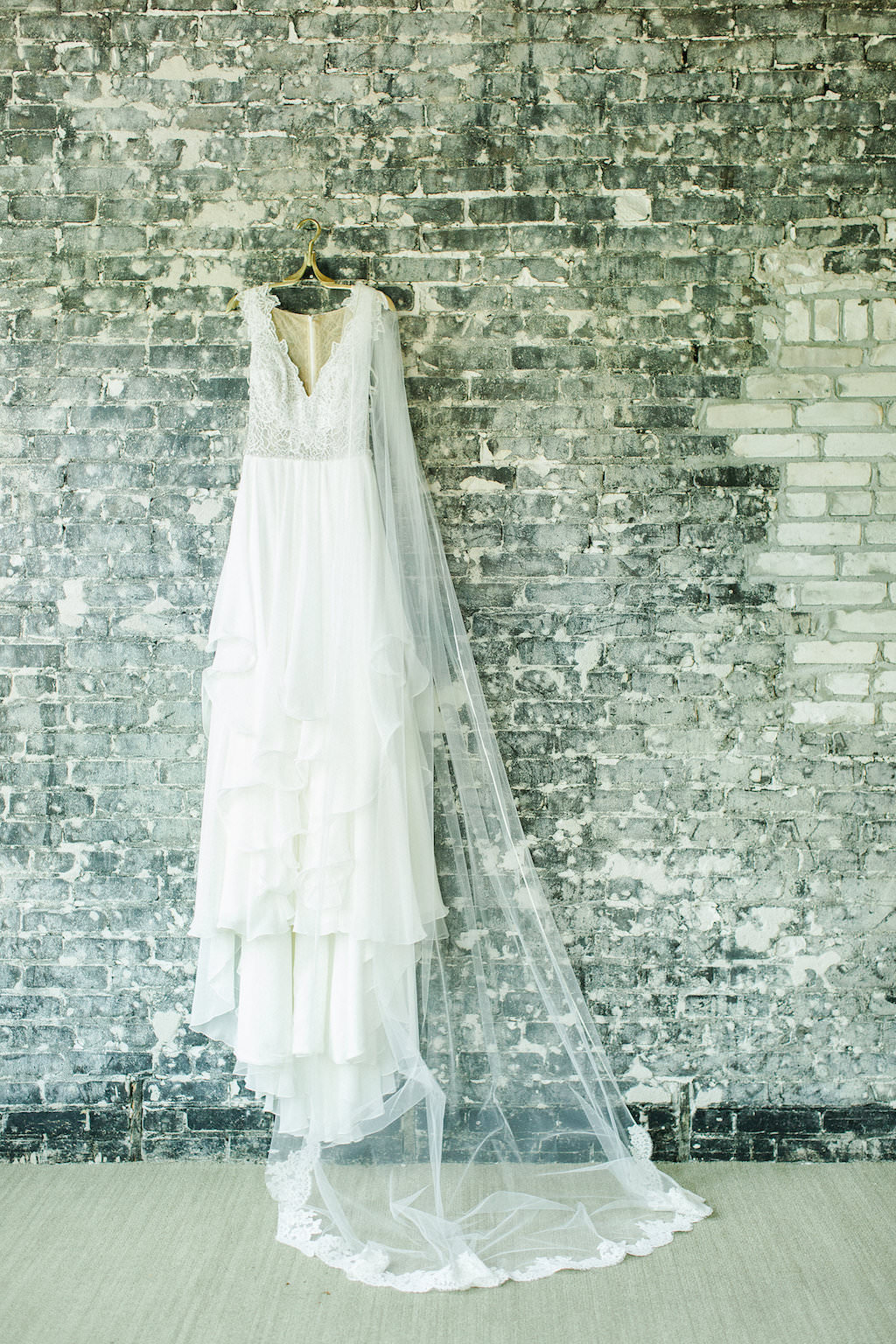 Lace Bodice Hayley Paige Wedding Dress with Veil on Hanger and Brick Wall