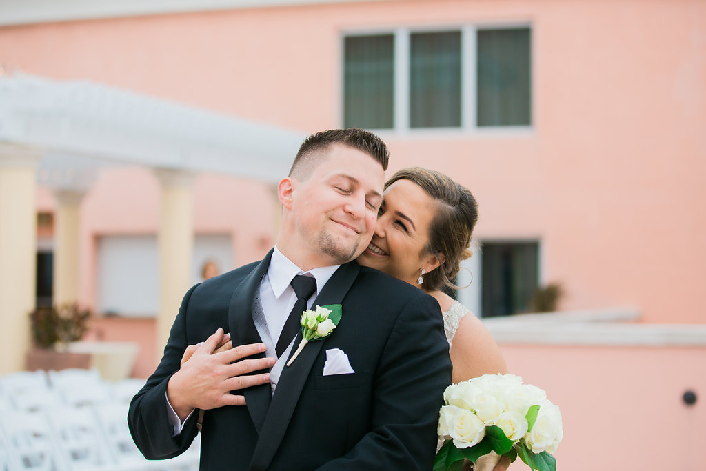 Outdoor Waterfront Hotel Rooftop Portraits, Bride with White Rose and Greenery Bouquet, Groom in Black Suit with Silver Vest and Boutonniere | Tampa Bay Wedding Photographer Kera Photography | Venue Hyatt Regency Clearwater Beach | Florist Apple Blossoms Floral Designs