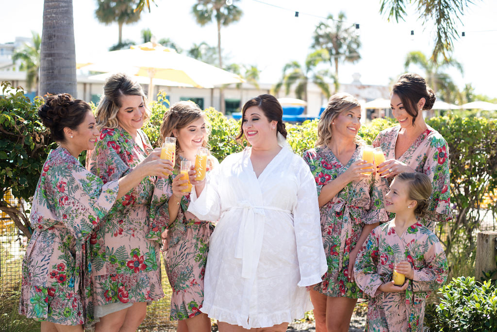 Outdoor Bridal Getting Ready Portrait with Mimosa Glasses Gold Lettering in matching PInk and Red Tropical Floral Silk Robes | Tampa Bay Wedding Photographer Caroline and Evan Photography