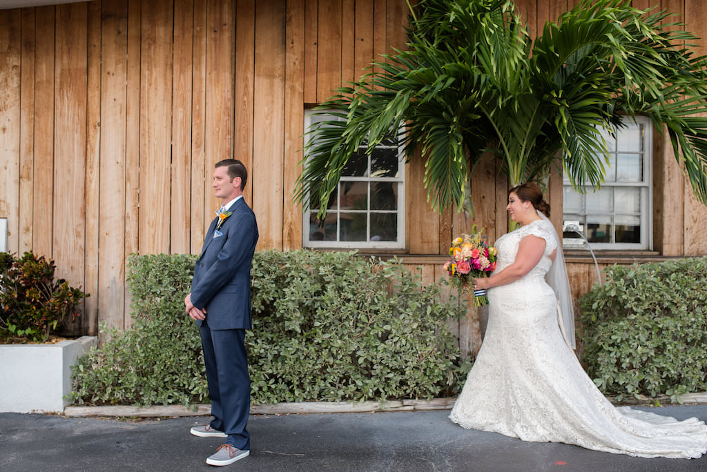 Outdoor First Look Portrait, Bride in Lace Cap Sleeve Dress with PInk and Orange Tropical Bouquet with Greenery and Striped Ribbon, Groom in Navy Suit with Boutonniere | St Pete Wedding Photographer Caroline and Evan Photography | Tampa Bay Wedding Dress Shop Truly Forever Bridal