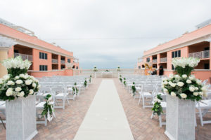 Waterfront Hotel Rooftop Elegant Wedding Ceremony with White Folding Chairs, White Rose and Greenery Floral Arrangements, and Fabric Aisle | Venue Hyatt Regency Clearwater Beach | Tampa Bay Wedding Planner Special Moments Event Planning | Florist Apple Blossoms Floral Designs