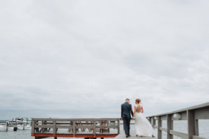 Outdoor Waterfront Wedding Portrait, Groom in Blue Suit with White Rose Boutonniere, Bride in Illusion Button Back Lace Dress | Tampa Bay Wedding Photographer Grind and Press Photography | Dunedin Venue Beso Del Sol