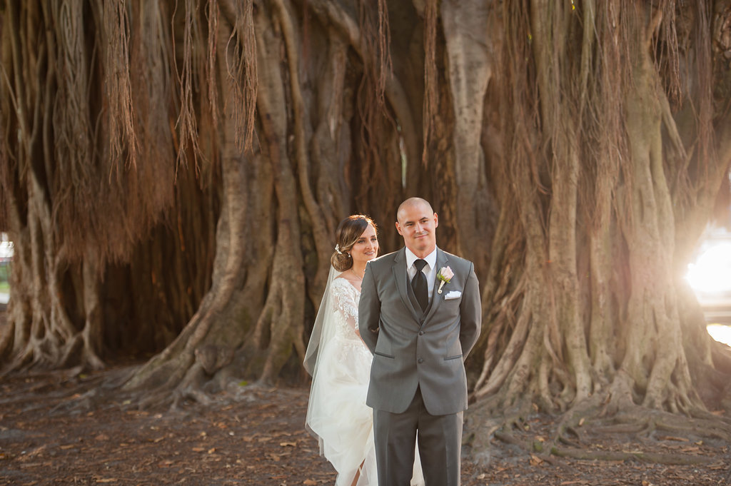 Outdoor First Look Wedding Portrait, Groom in Gray Suit with Blush Pink Rose and Greenery Boutonniere with Banyan Trees | Downtown St Pete Wedding Ceremony Venue North Straub Park
