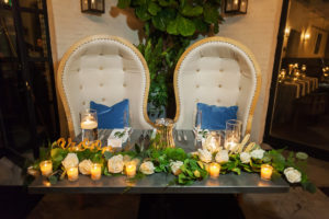 Modern, Industrial Chic Wedding Reception Sweetheart Table with White Rose and Greenery Garland Centerpiece with Votive Candles, Vintage White and Gold Oval Chairs with Blue Cushions, and Stylish Oversized Bride and Groom Signs | South Tampa Venue Oxford Exchange