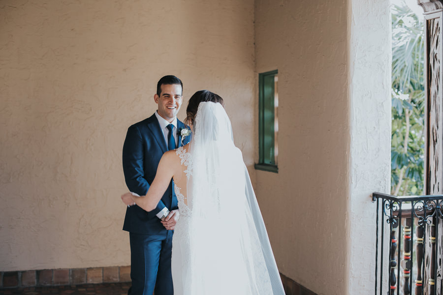 Outdoor Courtyard First Look Portrait, Bride with Long Comb Veil, Groom in Navy Blue Suit with White Rose Boutonniere | Sarasota Wedding Photographer Brandi Image Photography