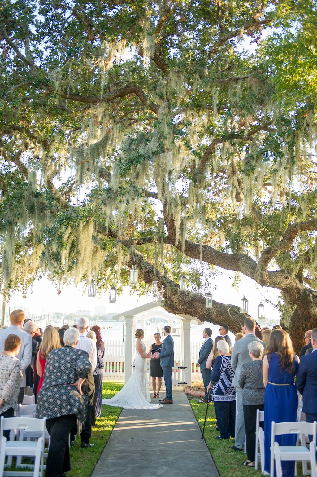 Outdoor Waterfront Wedding Ceremony Portrait with White Folding CHairs under Live Oak Tree with Spanish Moss and Hanging Hurricane Lanterns | Tampa Bay Wedding Photographer Andi Diamond Photography | Sarasota Wedding Venue Palmetto Riverside Bed and Breakfast