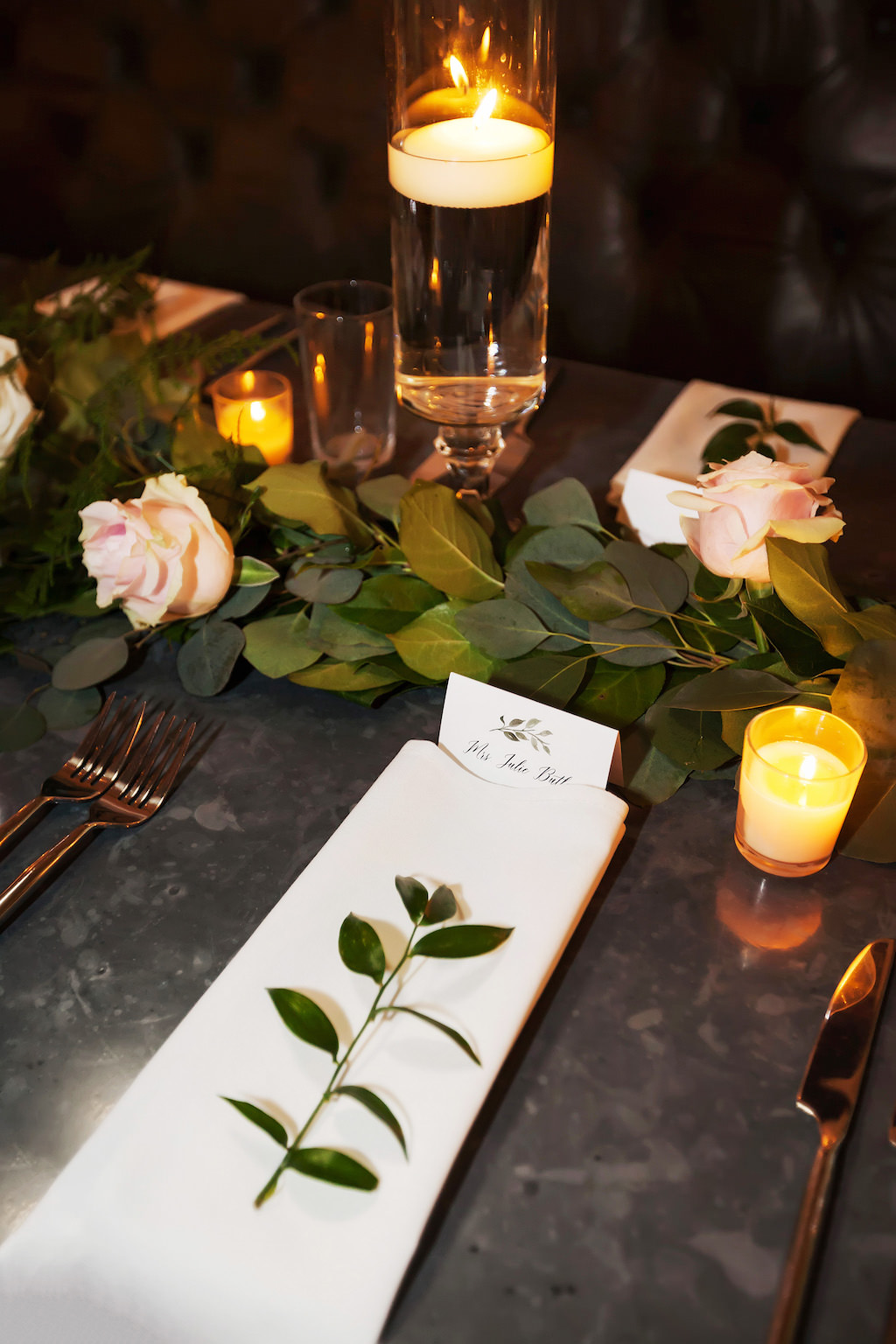 Modern Industrial Chic Wedding Reception Table Decor with White Linen, Printed Place Card, Pink Rose and Greenery Garland Centerpiece, and Floating Votive Candles in Glass Cylinder
