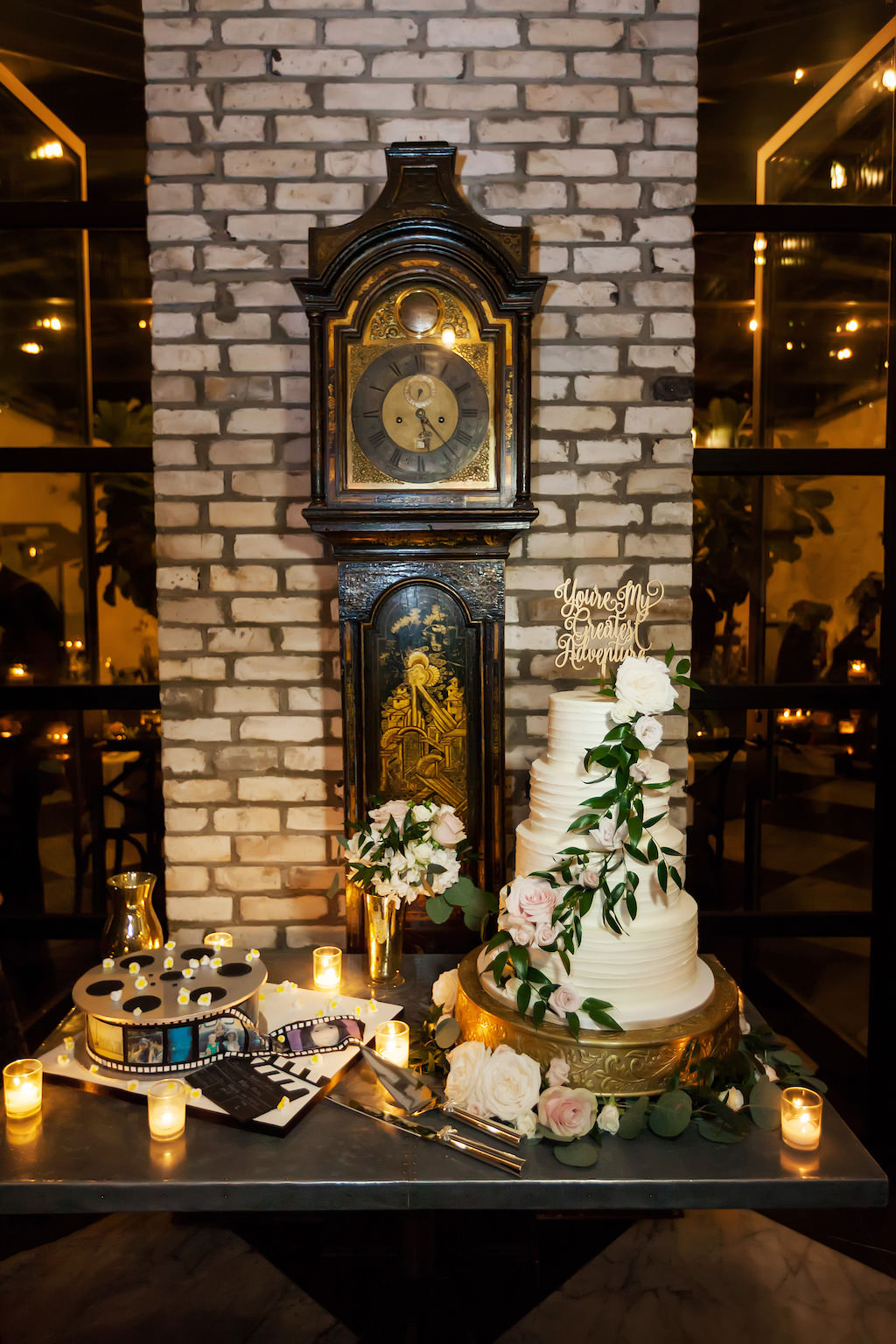 Industrial Chic Wedding Reception Dessert Table with Four Tier Round White Wedding Cake with Pink Floral and Greenery on Gold Cake Stand with Stylish Custom Cake Topper, and Film Reel Groom's Cake | Downtown Tampa Venue Oxford Exchange