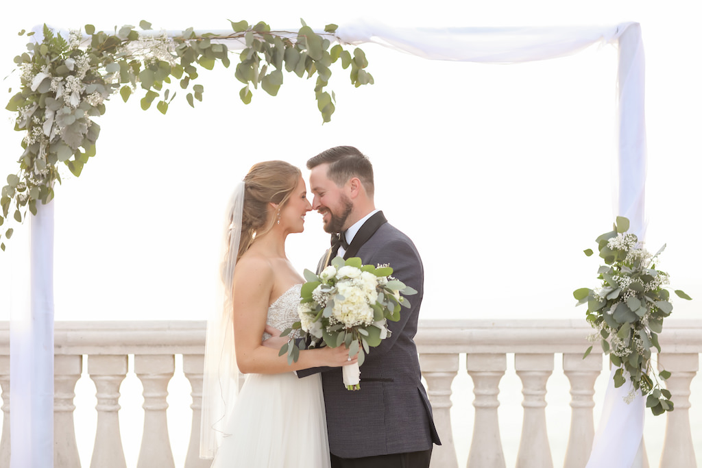 Outdoor Hotel Rooftop Wedding Ceremony Portrait, Bride in Strapless Wtoo Bridal Dress, Groom in Gray and Black Suit, Arch with Greenery and White Floral and Draping | Tampa Bay Hotel Wedding Venue Hyatt Regency Clearwater Beach | Photographer Lifelong Studios Photography
