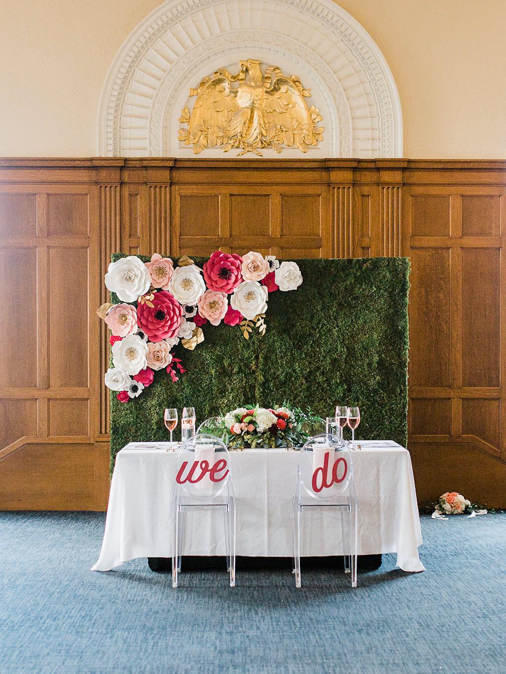 Hotel Ballroom Kate Spade Inspired Wedding Reception with Laser Cut Paper Flower Wedding Decorations in Blush Pink, White, Magenta and Gold on Moss Wall, White Linen Sweetheart Table with Armless Oval Ghost Chairs with We Do Oversized Letter Signs, White and Red Low Centerpiece with Greenery | Downtown Tampa Historic Hotel Venue Le Meridien | Rentals Kate Ryan Linens and Event Rentals