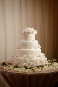 Four Tier Round White Wedding Cake with Floral Decorations and Rose Petals with Greenery