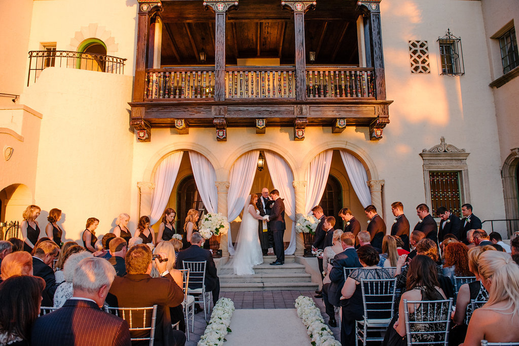 Elegant Outdoor Courtyard Wedding Ceremony Portrait with Silver Chiavari Chairs and White Floral lined Aisle, White Draped Backdrop, and Large Classical Copper Planters with Hydrangea and Greenery | Sarasota Historic Wedding Venue Crosley Powel Estate