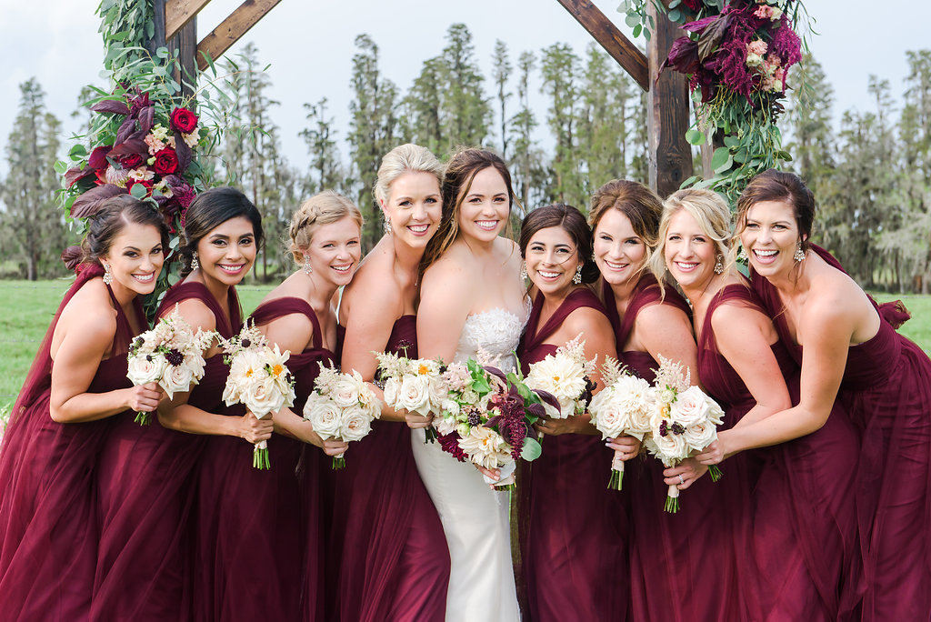 Outdoor Wedding Ceremony Bridal Party Portrait, Bride in Strapless Sweetheart Ines Di Santo Dress, Bridesmaids in Marsala Maroon Red Mismatched Jenny Yoo Dresses, with Wooden Cereemony Arch with Purple, Blush Pink and Greenery Florals and Bouquets