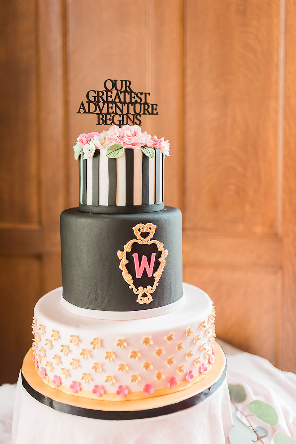 Three Tier Kate Spade Inspired Round Wedding Cake with Black and White Striped Fondant, Pink Icing Flowers with Greenery, Black Laser Cut Cake Topper, Icing Initial in Gold Frame on Gold Cake Stand