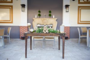 Outdoor Rustic Wedding Reception Simple Sweetheart Wooden Table with Oversized Gold Ampersand, Low Greenery Centerpiece, Votive Candles and Square Metal and Woven Chairs | Venue Palmetto Riverside Bed and Breakfast