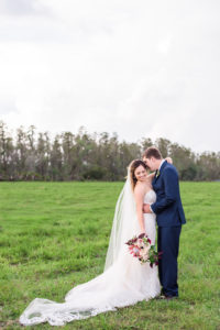 Outdoor Farm Wedding Bride and Groom Portrait, Groom in Navy Blue Suit, with Marsala Red Protea Bouquet with Greenery and BLush Pink Florals