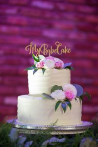 Two Tier ROund White Wedding Cake on Silver Cake Stand with White and Pink Rose with Greenery and Custom Gold Caketopper