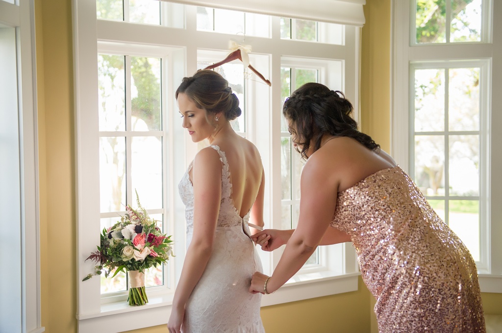 Bride Getting Ready Portrait in Open Back Illusion Lace Paloma Blanca Dress, Bridesmaid in Rose Gold Sequin Strapless Azazie Dress, with Burgundy, White Floral and Thistle Bouquet with Natural Greenery | Tampa Bay Wedding Photographer Andi Diamond Photography | Palmetto Hair and Makeup Femme Akoi Beauty Studio