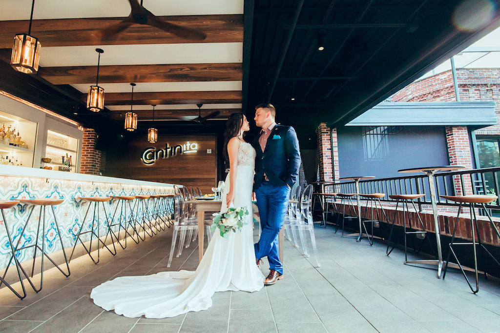 Industrial Chic Intimate Restaurant Bar Wedding Reception Portrait, Bride in Belted Column Dress with Greenery and White Floral Bouquet, Groom in Blue Suit with Pink Shirt | Modern Downtown St Pete Cantina Wedding Venue Red Mesa Events | Jennifer Matteo Event Planning
