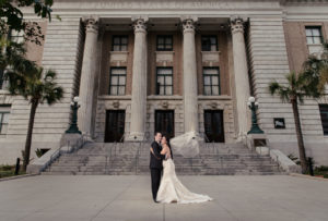 Outdoor Architectural Wedding Portrait, Bride in Floral Champagne Strapless Mermaid Wedding Dress, Groom in Black Tuxedo | Downtown Tampa Historic Hotel Venue Le Meridien