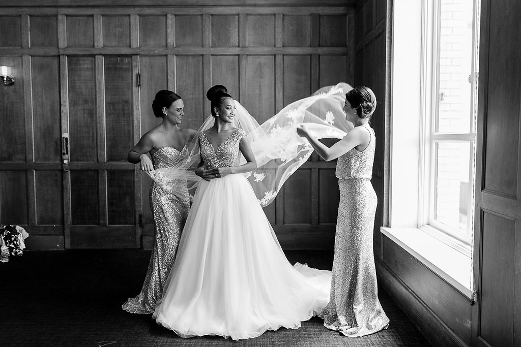 Indoor Bridal Party Getting Ready Portrait, Bride with Bun Updo, Beaded Bodice Wedding Dress with Full Layered Skirt and Floral Lace Veil, Bridesmaids in Mismatched Column Sequin Dresses