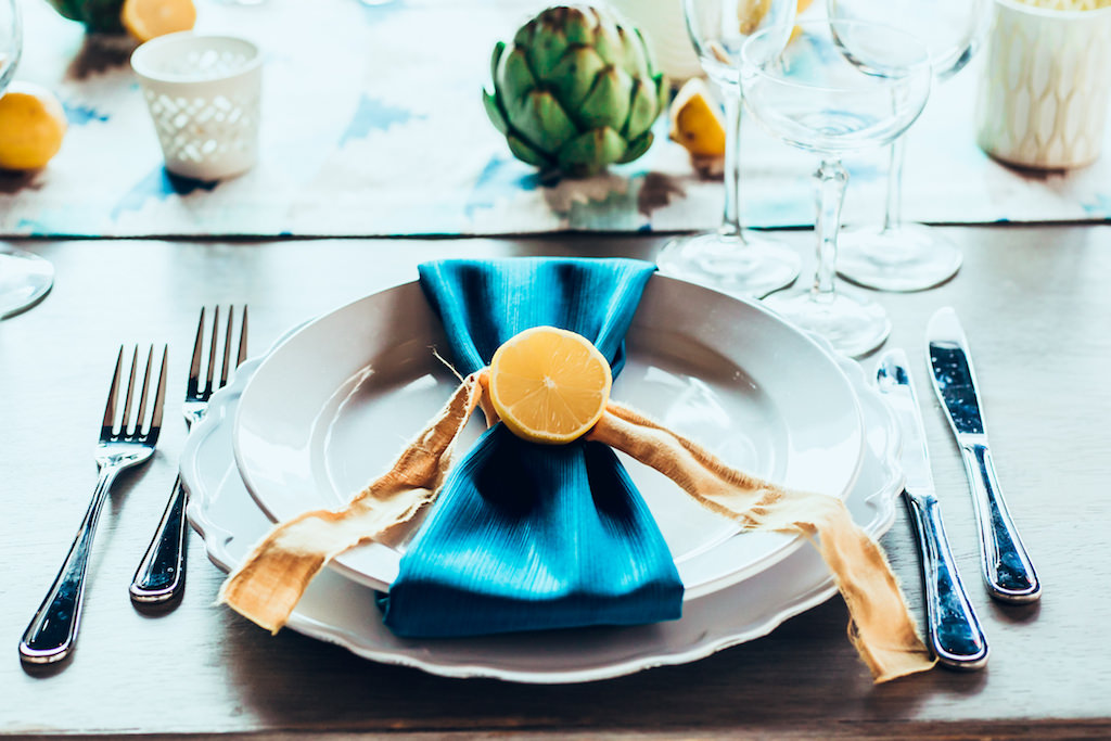 Summer Inspired Modern Wedding Reception Table Decor Setting with White Porcelain Votive Candleholders, Woven Canvas Table Runner, Turquoise Napkins, Cut Yellow Lemon and Artichoke Accents, White Porcelain Plate and Charger | Tampa Bay Wedding Planner Jennifer Matteo Event Planning