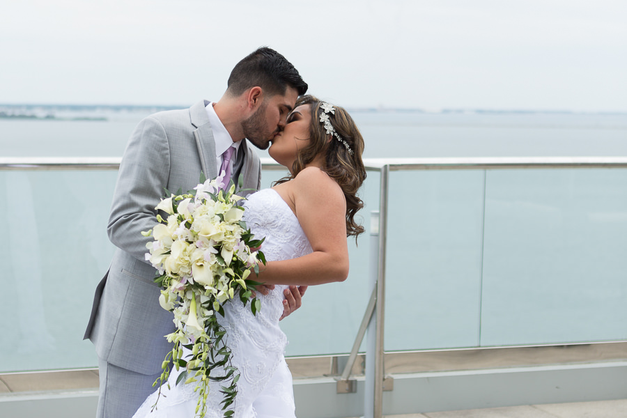 Outdoor Waterfront First Look Wedding Portrait, Bride in Strapless Belted Mermaid David's Bridal Dress, with White Floral Hair Accessory and White and Greenery Bouquet, Groom in Light Gray Suit with Lavender Purple Tie | Hotel Reception Venue The Westin Tampa Bay