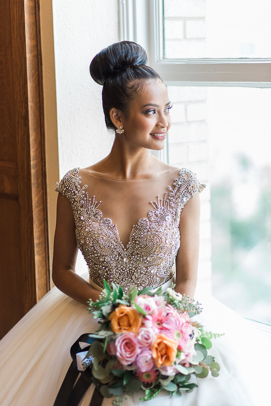 Indoor Bridal Portrait, Bride with Bun Updo, Beaded Bodice Wedding Dress with Full Layered Skirt, with Pink and Orange Rose with Greenery Bouquet with Black Ribbon | Tampa Bay Wedding Hair and Makeup Michele Renee The Studio
